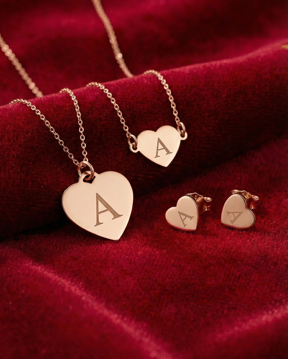 Rose gold jewelry set with heart-shaped pendants on a red fabric background