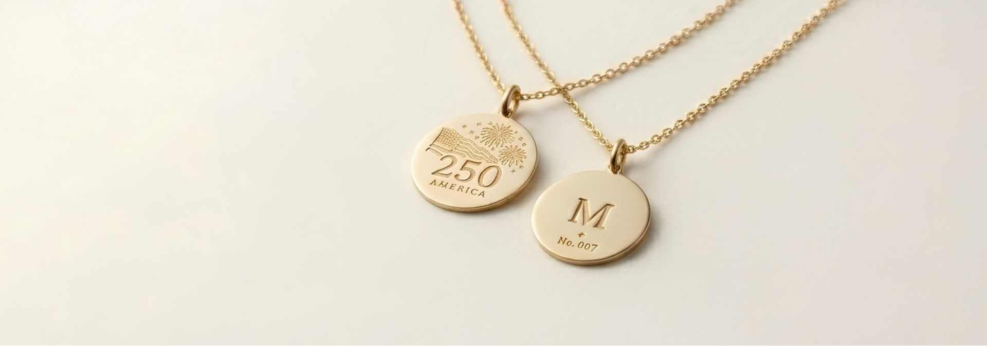 Two gold necklaces with engraved pendants on a light background