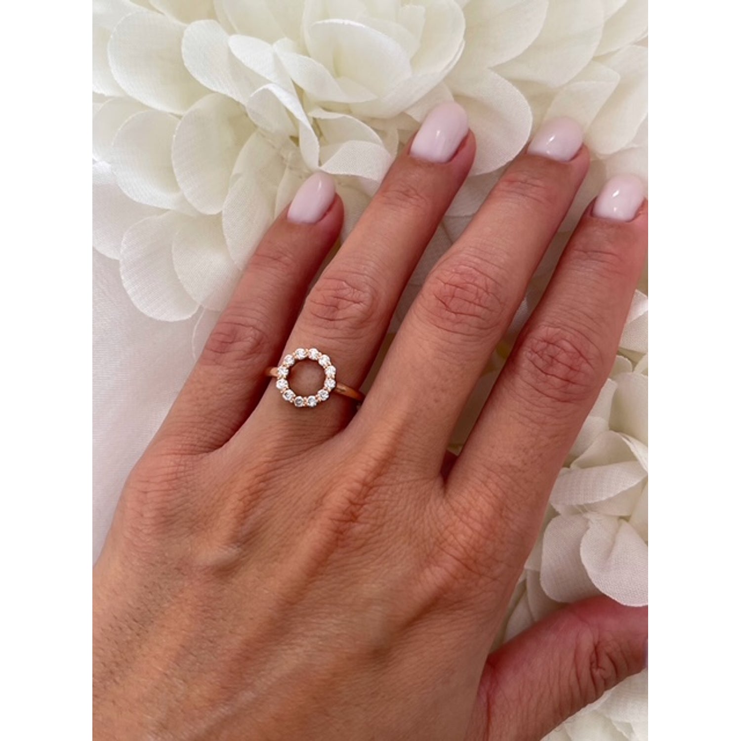 Hand wearing a diamond ring with a white floral background